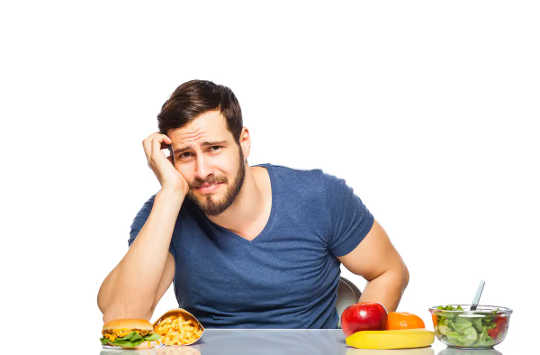 Man deciding between healthy and unhealthy food.