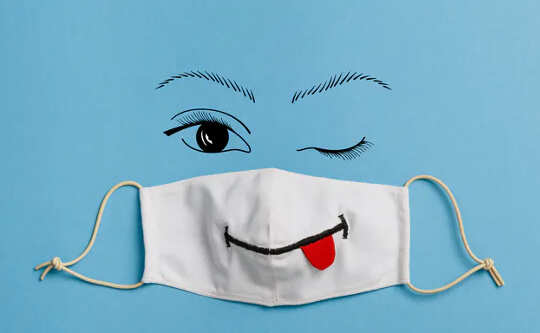 health mask with a smiley face drawn on it with tongue hanging out