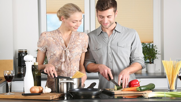 a man and woman preparing food together in the kitchen