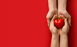 young hands holding a glowing red heart-shaped stone