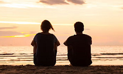 two people sitting by the ocean